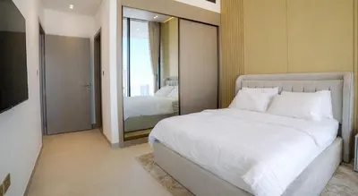 a bedroom with a large white bed and a mirror at Premium 1BR in JVC with Private Pool in Dubai