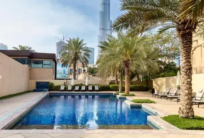 a swimming pool with palm trees and a building at Yansoon 3 Downtown, Dubai in Dubai