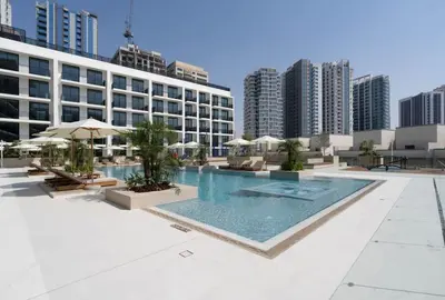 a pool with chairs and umbrellas on a building at Chic & Peaceful Studio Retreat Binghatti Aurora in Dubai