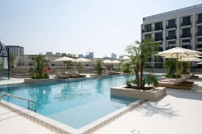a large swimming pool with chairs and umbrellas on a building at Chic & Peaceful Studio Retreat Binghatti Aurora in Dubai