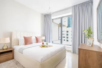 a white bedroom with a large bed and a large window at Frank Porter - 29 Boulevard Tower 2 in Dubai