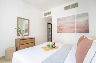 a white bedroom with a white bed and a dresser at Frank Porter - 29 Boulevard Tower 2 in Dubai