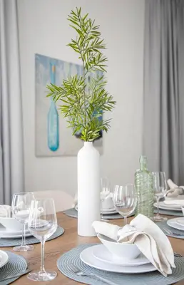 a dining room table with a white vase with a plant at Frank Porter - 29 Boulevard Tower 2 in Dubai