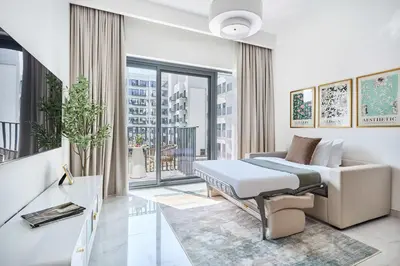 a bedroom with a bed and a couch and a window at Frank Porter - Azizi Beach Mirage in Dubai