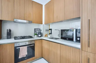 a kitchen with wooden cabinets and a stove at Frank Porter - Azizi Beach Mirage in Dubai