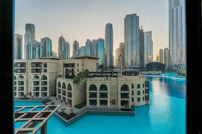 a large building with blue water in front of a city at Escape24 Upgraded 1BR Al Bahar with Partial Burj & Fountain View in Dubai