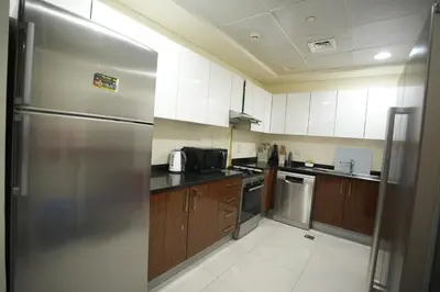 a kitchen with a stainless steel refrigerator and wooden cabinets at Marina bedspace Partial Sea View close to Tram in Dubai
