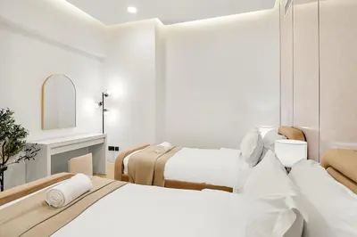a white bedroom with two beds and a mirror at FIRST CLASS 3BR Sea, Palm & Atlantis Views in Dubai