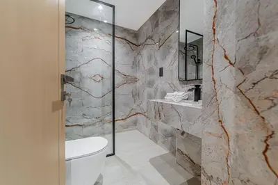 a bathroom with a toilet and a stone wall at Escape24 Brand New Designer 2Bedroom with fully Burj Khalifa Views in Dubai