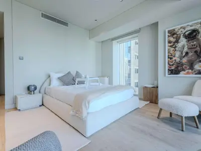 a white bedroom with a bed and a chair at Quiet Luxury and Views at The Address Dubai Marina in Dubai