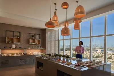 a woman standing in a kitchen with a counter with food at Elegant Studio Apartment with Marina View JVT in Dubai