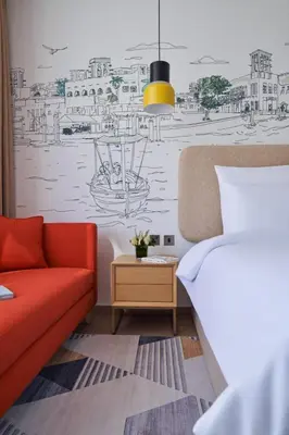 a living room with a red couch and a drawing on the wall at Elegant Studio Apartment with Marina View JVT in Dubai