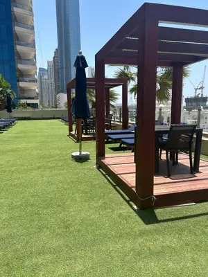 a gazebo with a table and chairs on the grass at Silk Valley - Luxury 1BR | High Floor & Balcony | Sea Views in Dubai