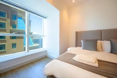 a bedroom with a bed with a large window at Silk Valley - Luxury 1BR | High Floor & Balcony | Sea Views in Dubai