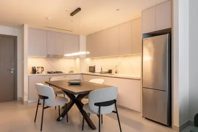 a kitchen with a table and chairs and a refrigerator at Modern 1BR in Beach Mansion with Pool and Gym in Dubai