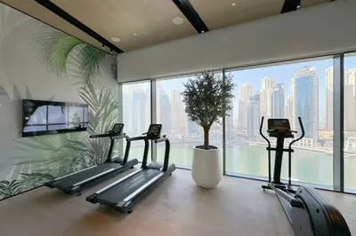 a gym with three tread machines and a large window at Vida Marina Residence High Floor Luxury 1 BR Flat in Dubai