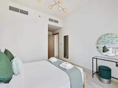 a white bedroom with a bed and a mirror at Enchanting 2BDR In Creek Harbour 19 in Dubai