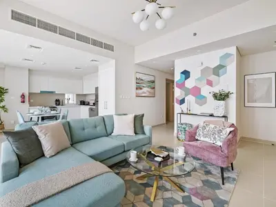 a living room with a blue couch and a pink chair at Enchanting 2BDR In Creek Harbour 19 in Dubai