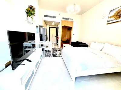 a white bedroom with a white bed and a dining room at 16 Studio in Skyz By Danube, Arjan in Dubai