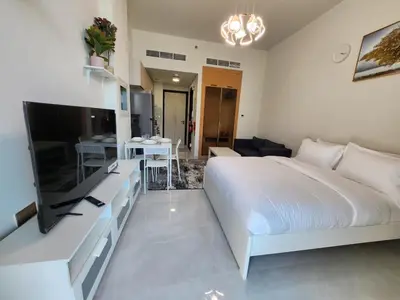 a bedroom with a large white bed and a living room at 16 Studio in Skyz By Danube, Arjan in Dubai