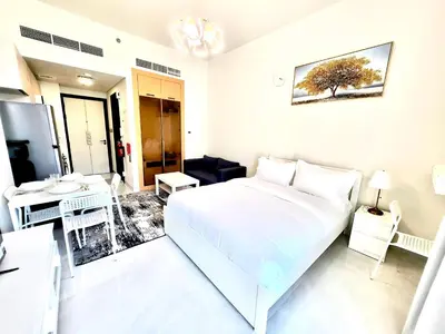 a white bedroom with a bed and a desk at 16 Studio in Skyz By Danube, Arjan in Dubai