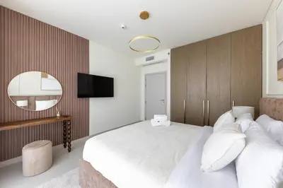 a bedroom with a large white bed and a mirror at Spacious 1BR at Beach Mansion Balcony, Pool and Gym in Dubai