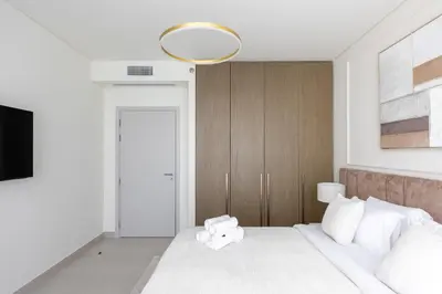 a bedroom with a large white bed with a mirror at Spacious 1BR at Beach Mansion Balcony, Pool and Gym in Dubai