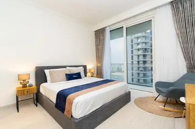 a bedroom with a bed and a large window at CitiHome Elegant 2BR - Private Beach and Marina View in Dubai