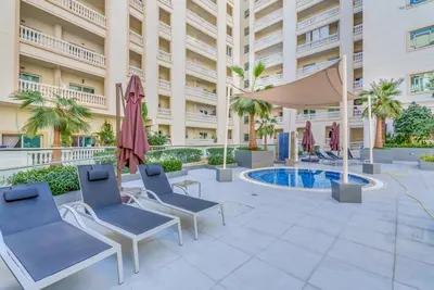 a patio with chairs and umbrellas in front of a building at Waves - Elegant 1BR Retreat in JVC with Balcony in Dubai
