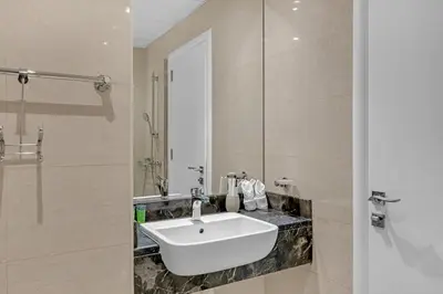 a bathroom with a white sink and a mirror at Waves - Elegant 1BR Retreat in JVC with Balcony in Dubai