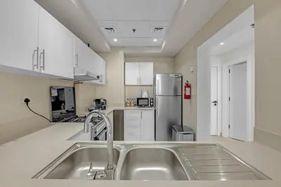 a kitchen with a sink and a refrigerator at Waves - Elegant 1BR Retreat in JVC with Balcony in Dubai