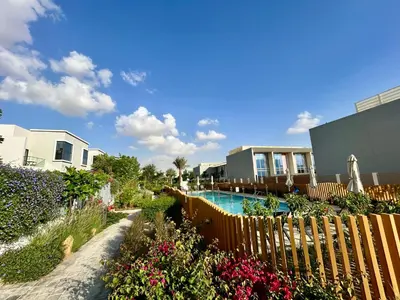 a swimming pool with a fence and flowers at Modern brand new Loft Townhouse in Dubai in Dubai
