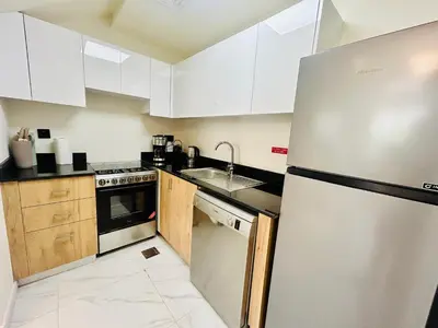 a kitchen with white cabinets and a stainless steel refrigerator at Modern brand new Loft Townhouse in Dubai in Dubai