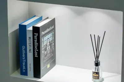 a shelf with several books and a vase with sticks at DAMAC Aykon Tower - High-Floor Luxury 2-Bedroom Apartment in Dubai