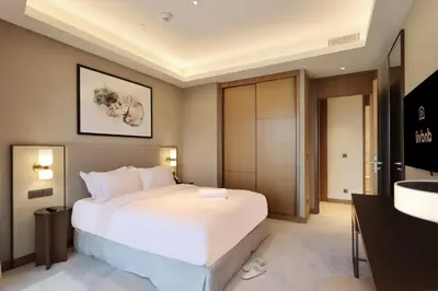a bedroom with a large white bed and a television at 3B in Downtown with Burj Khalifa View Near Dubai Mall and Opera District in Dubai