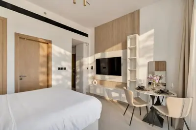 a bedroom with a white bed and a table with chairs at Modern Studio Apartment in Binghatti Tulip with Pool, Parking, Gym in Dubai