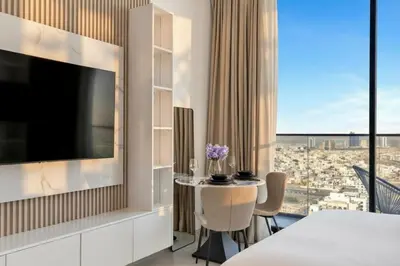 a room with a large television and a table with chairs at Modern Studio Apartment in Binghatti Tulip with Pool, Parking, Gym in Dubai