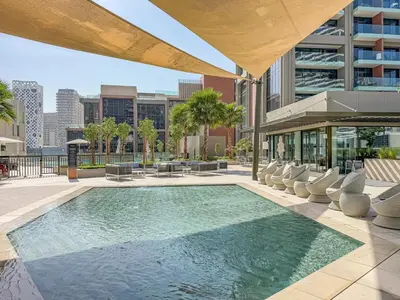 a swimming pool with chairs and a building at Elegant Studio with Iconic Burj Khalifa Views in Dubai