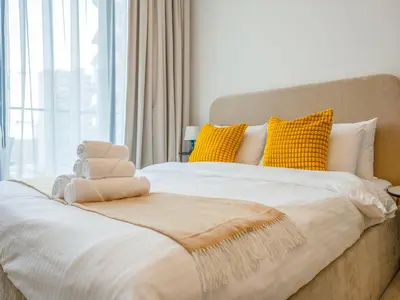 a bedroom with a large bed with yellow pillows at Dubai Miracle Garden Modern Luxury Studio Pool, Padel Court & Sauna Arjan in Dubai