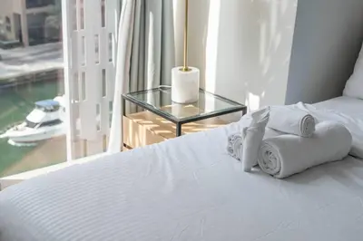 a bedroom with a bed with towels and a glass table at Marina | Canal View Studio in Cayan Tower in Dubai