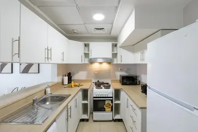 a kitchen with white cabinets and a stove top oven at Modern Comfort - Convenient - Prime JLT Living in Dubai