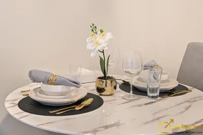 a table with plates and glasses and flowers on it at Luxury Studio in Dubai Hills by Deleguest in Dubai
