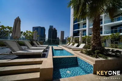 a swimming pool with chaise lounge chairs and a building at Elegant Studio Living in Privé in Dubai