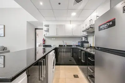 a large kitchen with black and white counters and appliances at Spacious 1BR Elite Business Bay Residence in Dubai