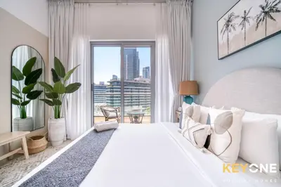 a white bedroom with a large bed and a large window at Modern One Bedroom with Stylish Touches in Dubai