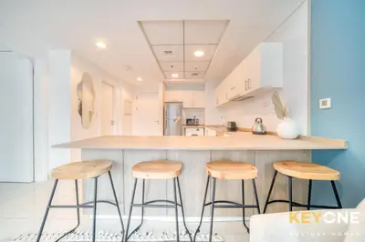 a kitchen with wooden stools at a counter at Modern One Bedroom with Stylish Touches in Dubai