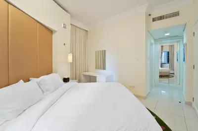 a bedroom with a large white bed and a hallway at Next to Dubai Mall & Burj Khalifa I Luxury Design in Dubai