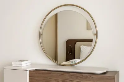a round mirror on a white wall next to a table at Elevated 1BR with Private Pool at Binghatti Phantom in Dubai