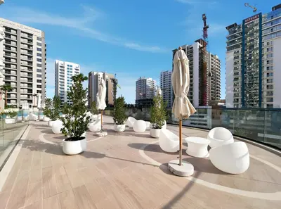 a rooftop patio with umbrellas and trees and buildings at Elevated 1BR with Private Pool at Binghatti Phantom in Dubai
