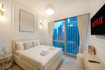 a bedroom with a white bed and a large window at Stunning 2BR Burj Khalifa View from Infinity Pool Grande Signature Residences in Dubai